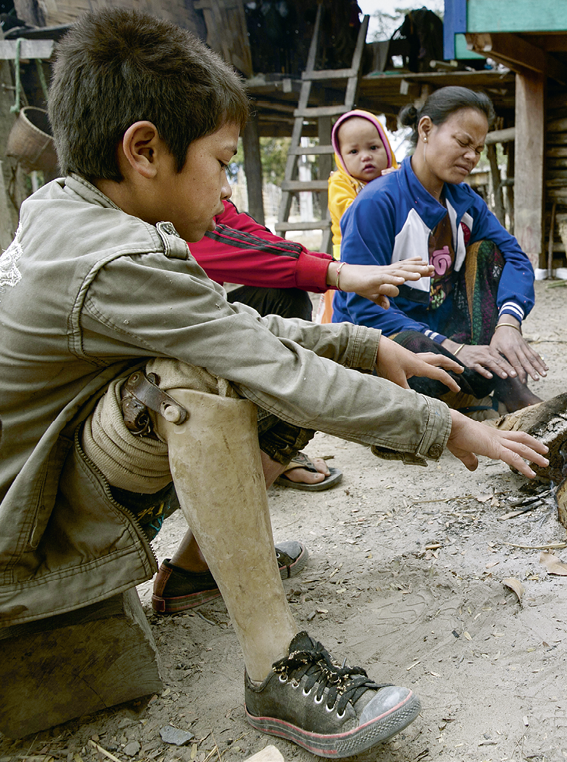 Province de Savannakhet, village de Tomlaung  Un petit gar on, victime de l'explosion d'une mine, et sa famille se r chauffent autour d'un feu  Savannakhet Province, Tomlaung village  A little boy, victim of a mine explosion, and his family gather around a fire to keep warm  Il a perdu sa jambe dans un accident de mine  L'accident a eu lieu le 23 janvier 2012, lorsque les familles se sont r unies autour du feu pour se r chauffer  La mine  tait enfouie sous la terre et a explos , tuant 4 personnes de plusieurs familles du petit village  The little boy lost his leg in a mine accident  The accident happened on 23 January 2012, when families were gathered around a fire to keep warm  The mine was buried in the ground and exploded, killing 4 people from various families in the small village 
